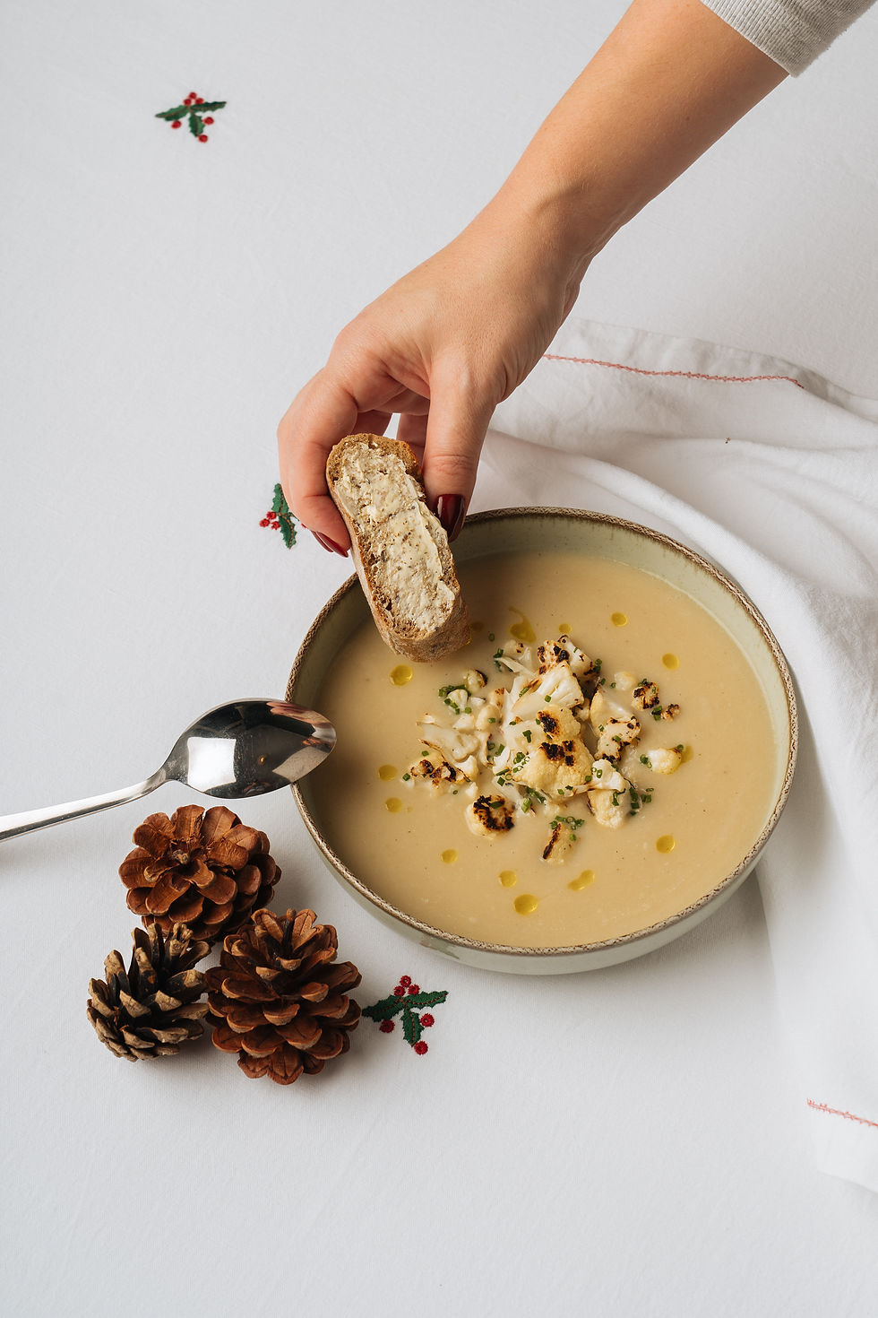 Velouté van geroosterde bloemkool met truffel, met een stukje brood dat in de soep gedoopt wordt