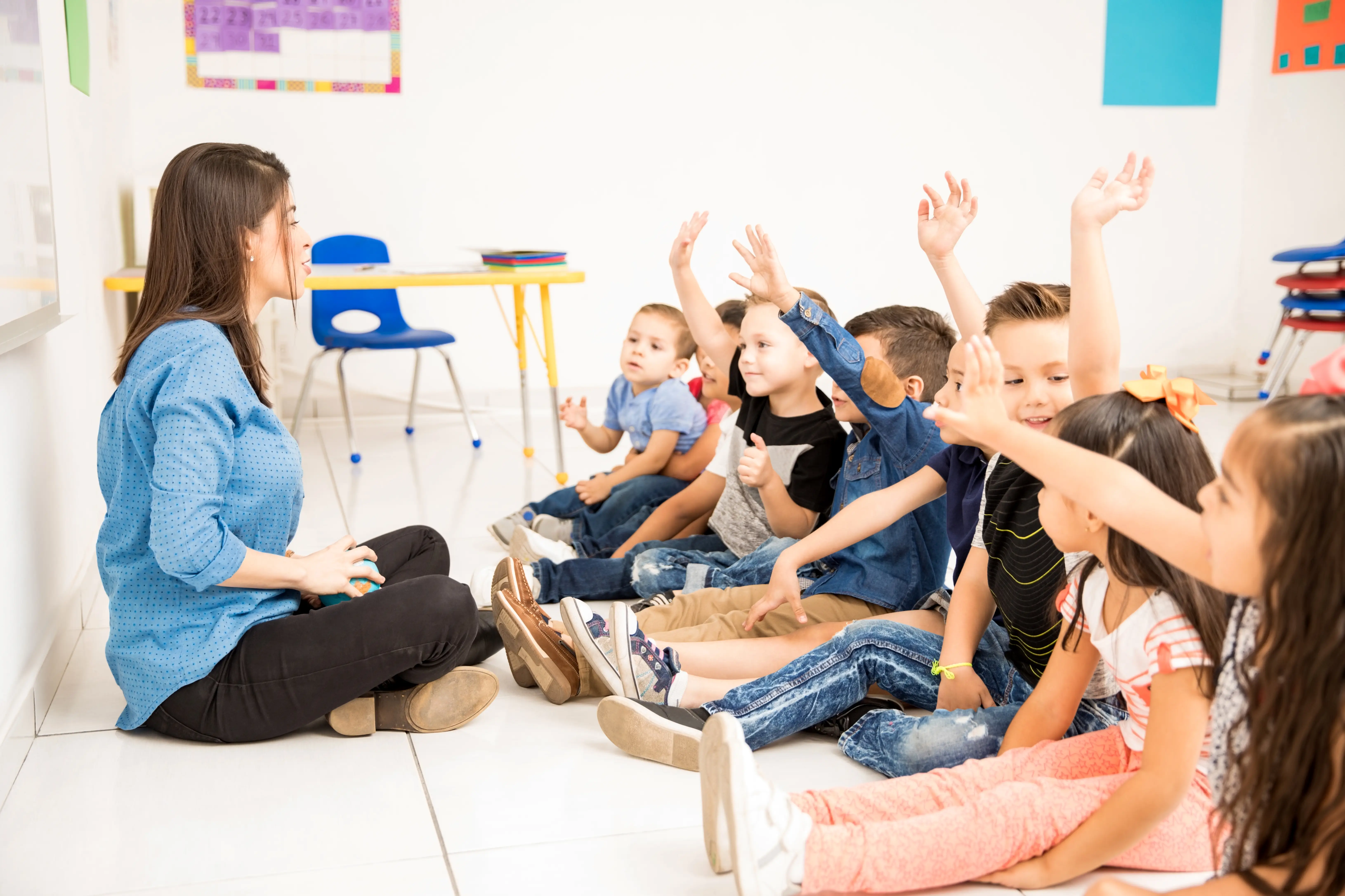 Professora em sala de aula de educação infantil com presente de dia dos professores