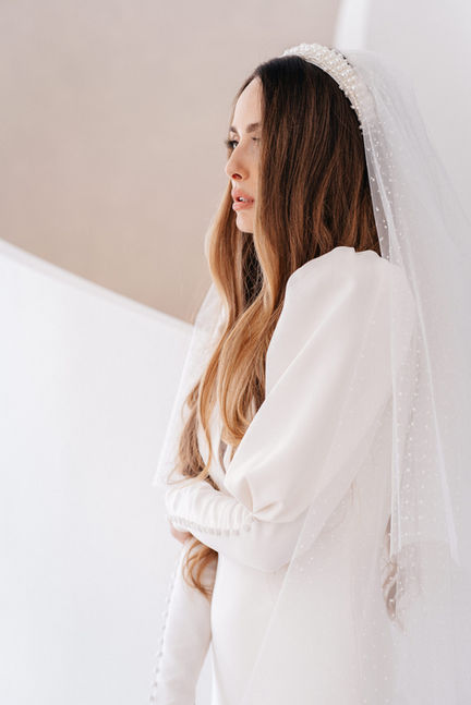 A bride with flowing hair and a long, pearl-studded veil, captured in soft, natural light in Chateau de Frontiere.