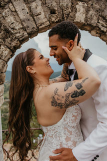 Happy bride and groom embracing under a stone arch