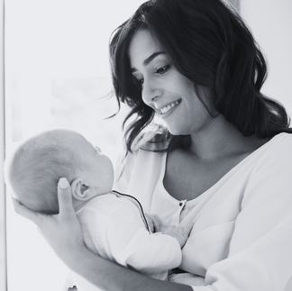 black and white image of mother smiling at newborn baby