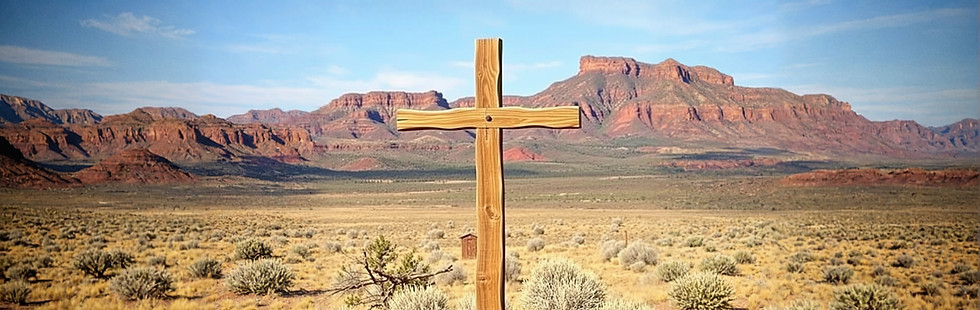 Picture of a wooden cross statue in front of a landscape that would be found on the plains