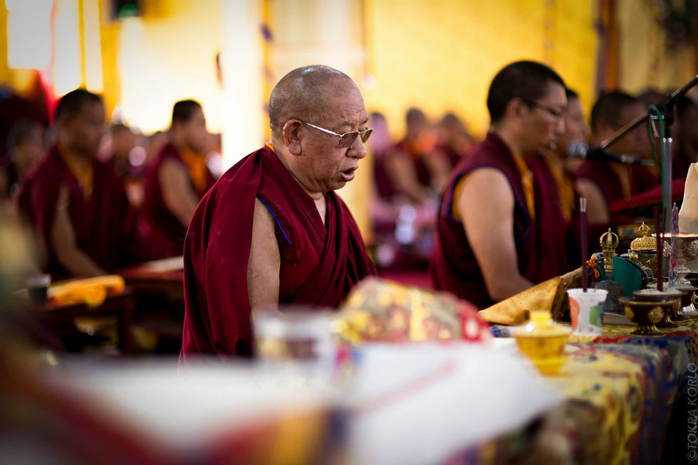 A bespectacled robed figure seated at a table of ritual objects in warm window light — Shar Minub Institute, Kathmandu, Nepal — July 2014 — Shamar Rinpoche - Shar Minub — photograph by Tokpa Korlo