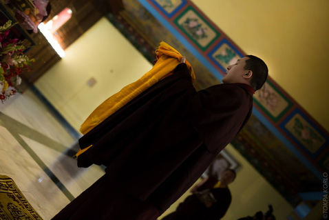 Low-angle portrait of a maroon-robed attendee in the temple interior — Karmapa International Buddhist Institute, New Delhi, India — December 2014 — KIBI Winter Retreat 2014 - Part 1 — photograph by Tokpa Korlo