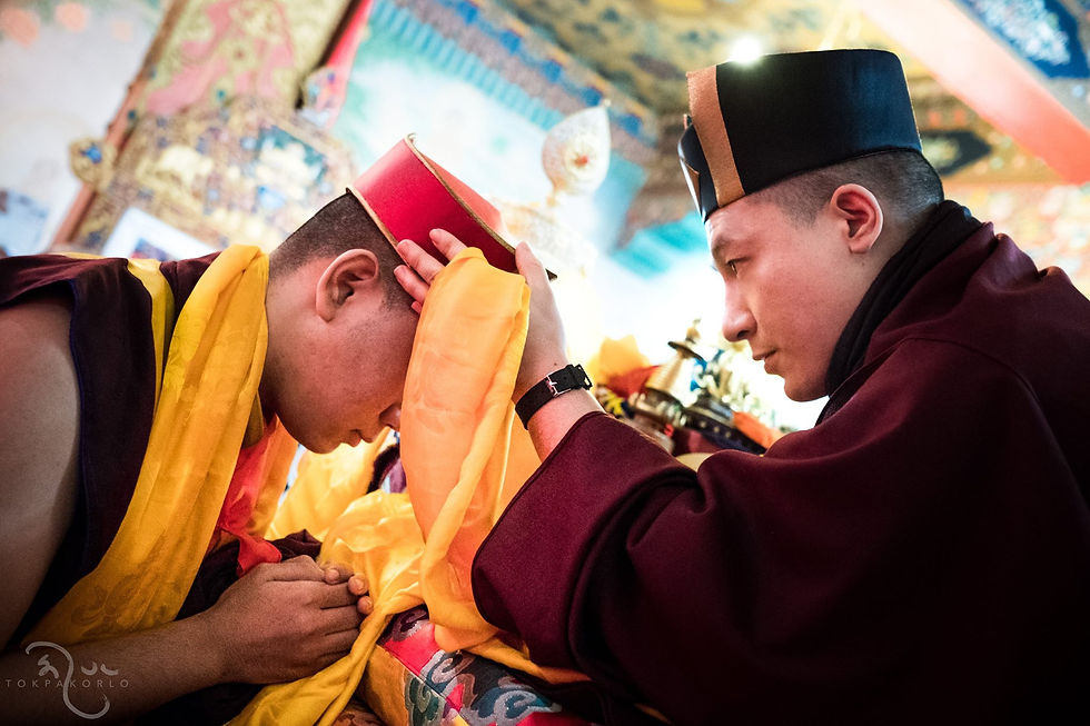 Two figures in ceremonial robes and tall hats lean toward one another during a formal exchange — Bodh Gaya, Bihar, India — Dec 11, 2016 — Monlam - The Gift Of The Red Crown — photograph by Tokpa Korlo