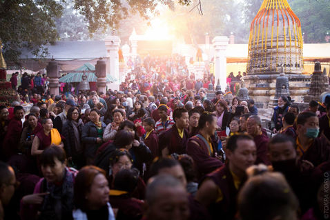 A vast crowd gathers beneath glowing sunlight beside the temple — Bodh Gaya, Bihar, India — December 2014 — Monlam 2014 - Day 7 - Dreams, Goodbyes and Memories — photograph by Tokpa Korlo