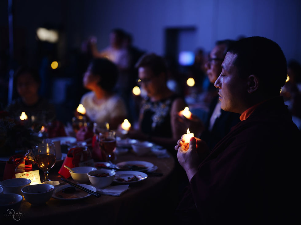 Guests sit together at a dimly lit evening gathering, with soft blue light and table settings in the foreground — Singapore — Sep 30, 2025 — Singapore 2025 - Now It Comes To A Close — photograph by Tokpa Korlo