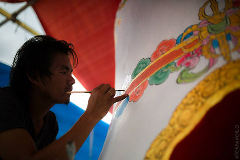 Silhouetted painter carefully outlining a gold-and-red border — Shar Minub Institute, Kathmandu, Nepal — October 2014 — Shar Minub Cremation Stupa — photograph by Tokpa Korlo