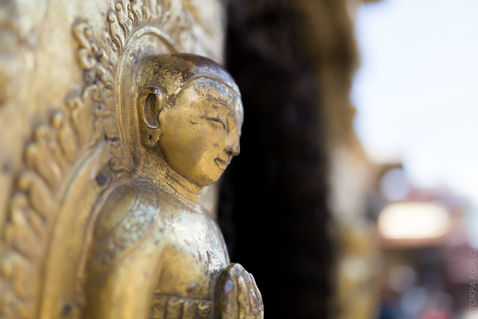 Close side view of a weathered gilded statue against a softly blurred background — Swayambhunath, Kathmandu, Nepal — October 2014 — Shar Minub - A Sunny Afternoon at Swayambhu — photograph by Tokpa Korlo