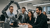 Corporate professionals in the UK engaging with advanced robotics during a hands-on bootcamp, smiling and collaborating in a modern training environment.