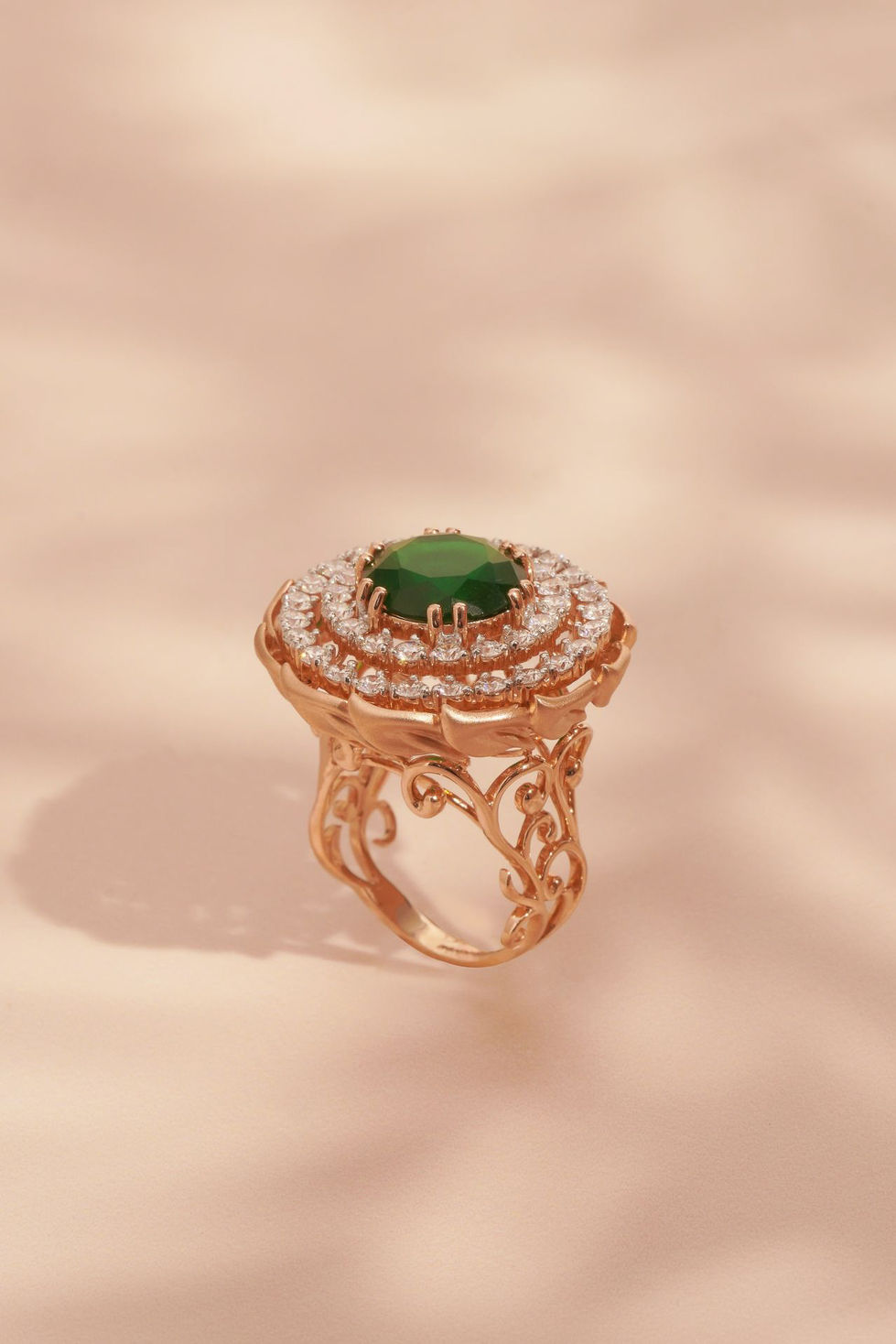 Ornate gold ring with green gemstone and diamonds.