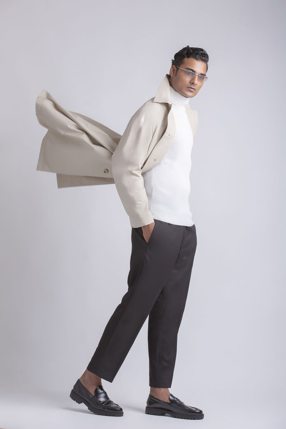 Person in stylish outfit with coat and glasses.