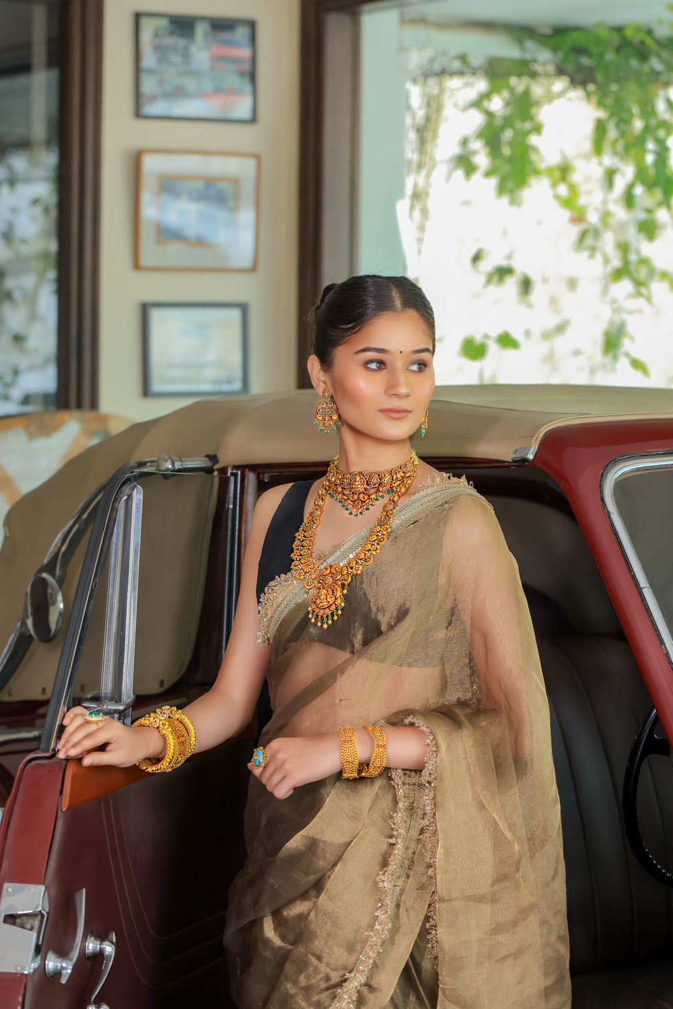 Woman in elegant traditional attire by vintage car.