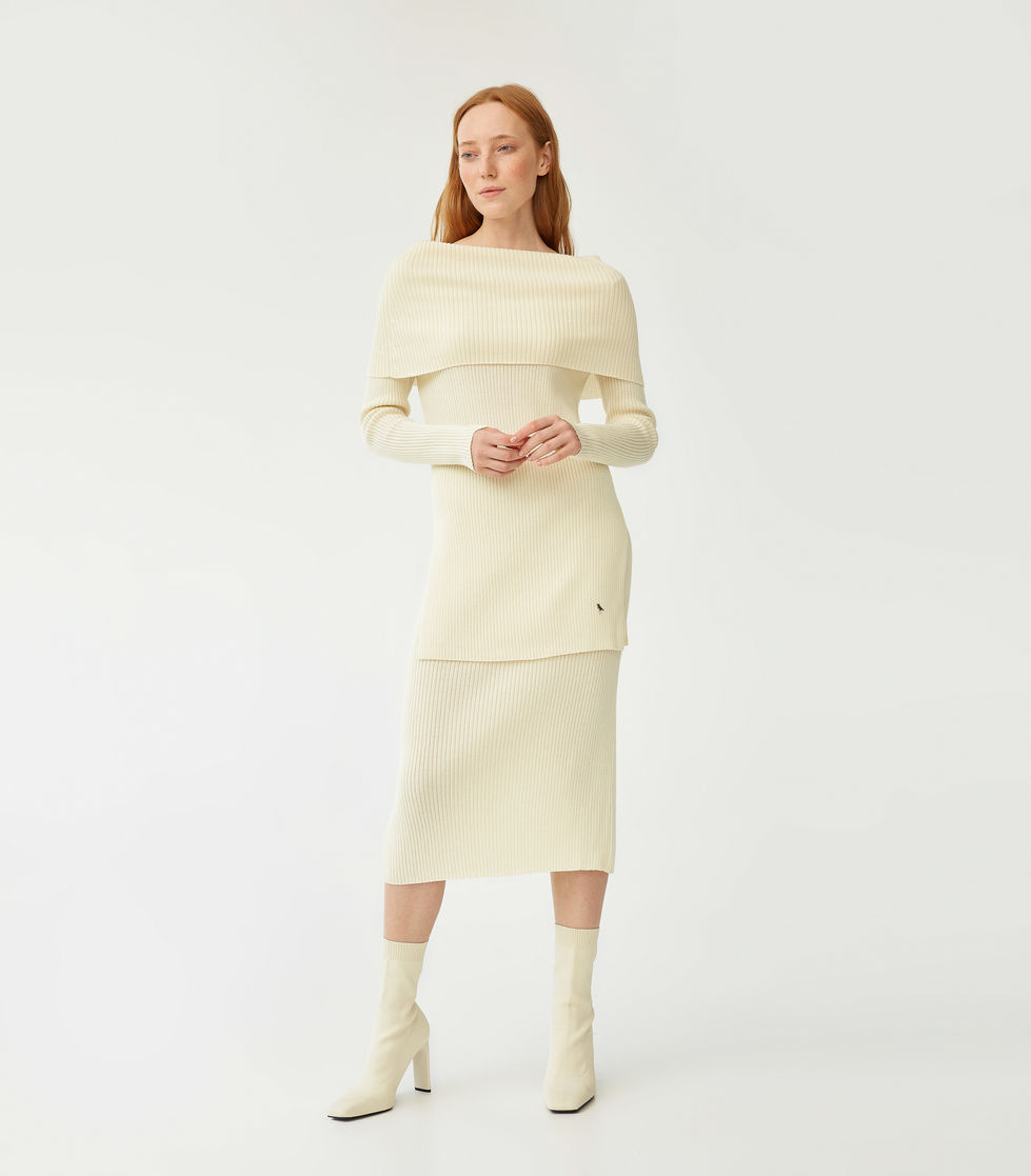 Woman in elegant off-white dress and boots.