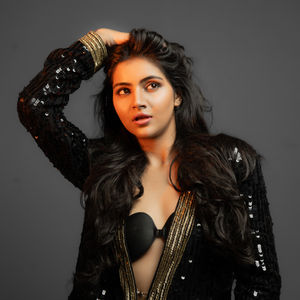 Woman posing in black sequin outfit, dramatic lighting.