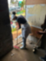 Volunteer sweeping a floor during community missions work