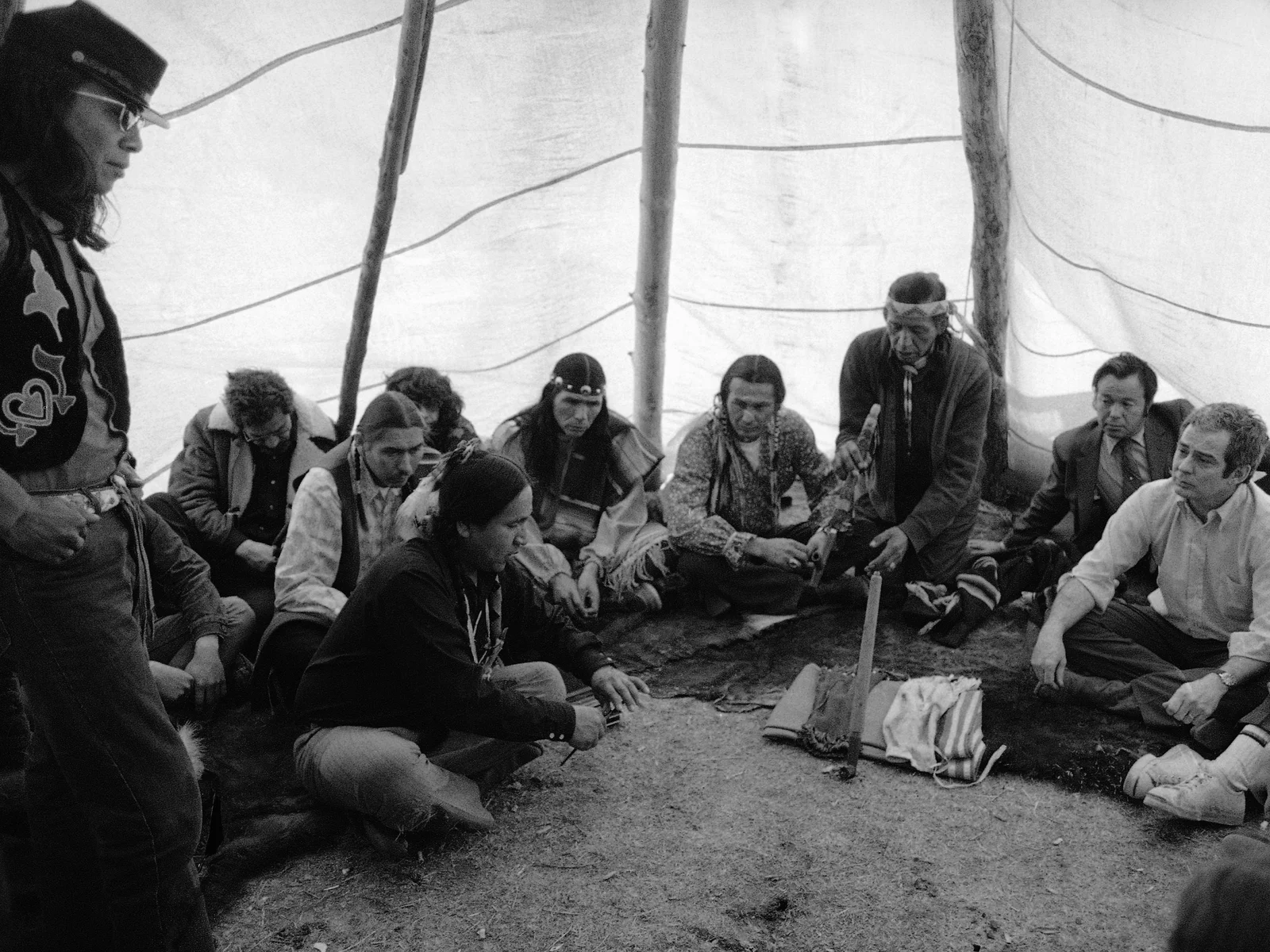 Group of Indigenous people sitting under a tipi