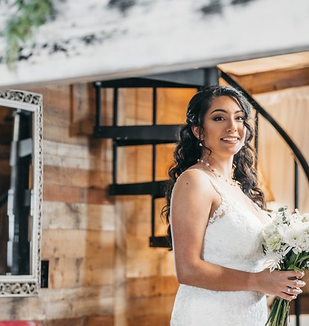 Smiling bride holding a bouquet indoors at Rayshell Ranch.