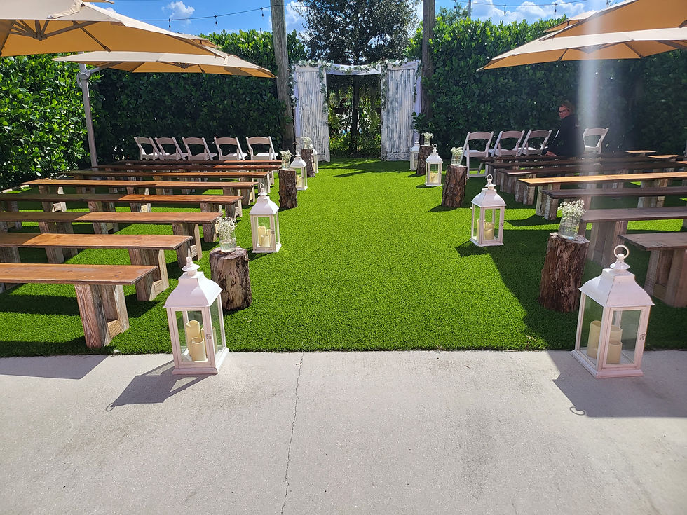 Outdoor ceremony lawn with wooden benches, floral arch, white lanterns, and trees in the background at Rayshell Ranch.