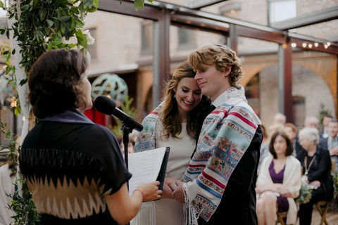 a bride and groom wrapped in a Tallit at their Jewish wedding in New York City, New York
