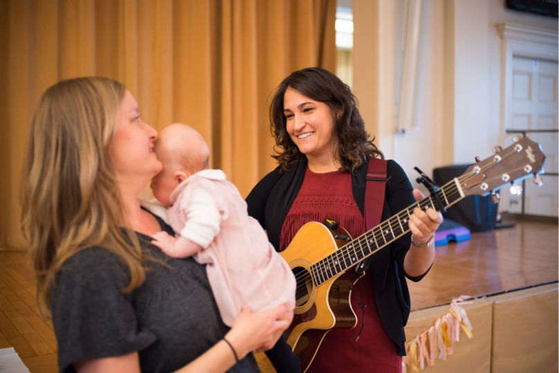 Cantor Stein playing guitar for a young mother and her baby at a Jewish Baby Naming ceremony in New York City, New York