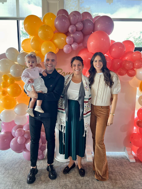 Young parents and their baby in front of a balloon display with Cantor Stein at their Jewish baby naming at The Connecticut Shoreline