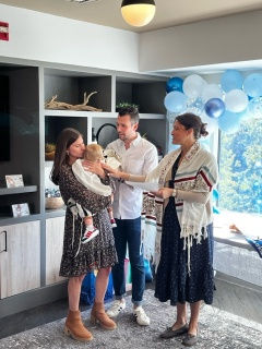 A young mother hugging her baby, with the father and Cantor Stein at a Jewish baby naming in Rye, New York