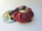 Un sac rouge avec glands et cymbales dorées sur fond clair.
