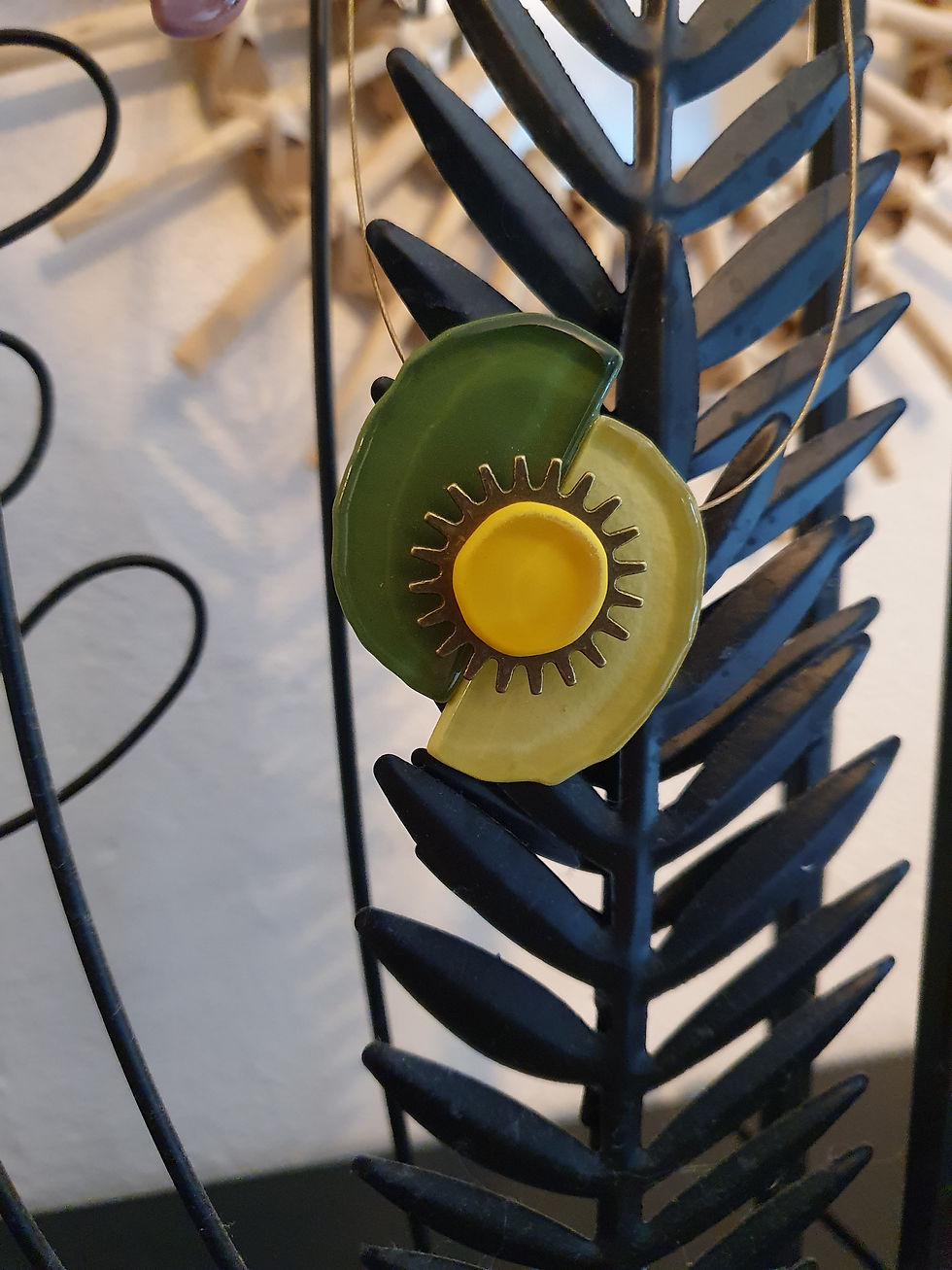 Collier fantaisie vert et jaune, D'Ici et de Claire, sur fond de fer forgé.