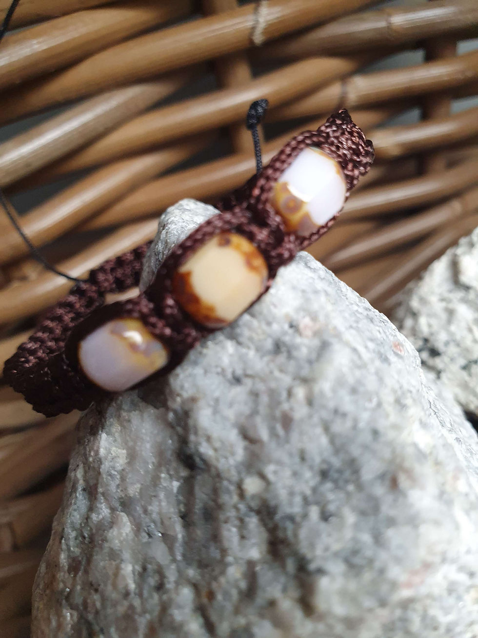 Miniature : Bracelet marron avec des perles beiges posé sur un rocher. D'Ici et de Claire