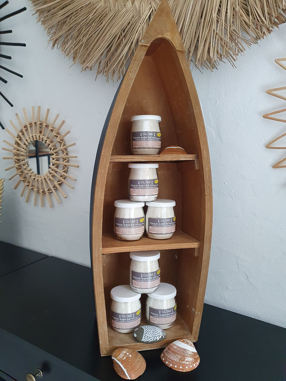 Étagère en bois en forme de bateau, avec plusieurs petits pots décoratifs. D'Ici et de Claire