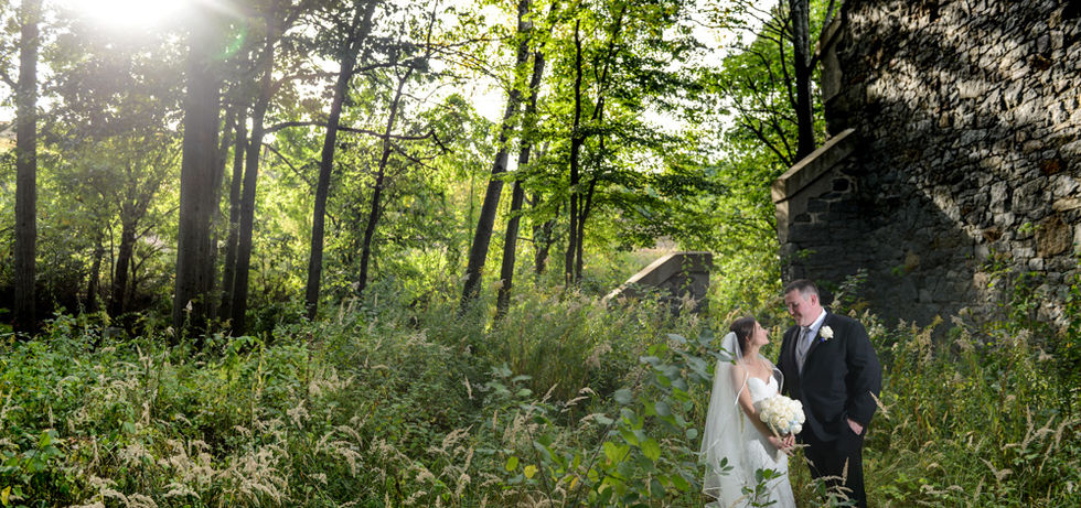 Overgrown foliage taking over old stone ruins at Granite Links in Quincy, MA with bride and groom lost in the scene but lit perfectly with flash to create a unique and stunning wedding photo that looks like something out of a movie.