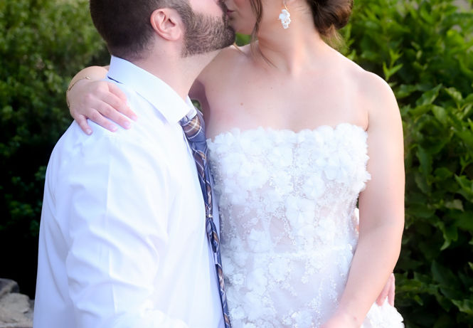 Bride sitting on grooms lap kissing outside the Grand Ballroom of The Villa in East Bridgewater MA