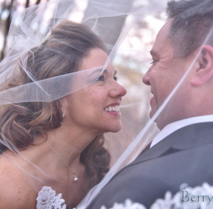 Bride and groom take a quiet moment under her veil to share a kiss showing past-peak fall foliage is still good at Camp Bournedale in Bourne MA