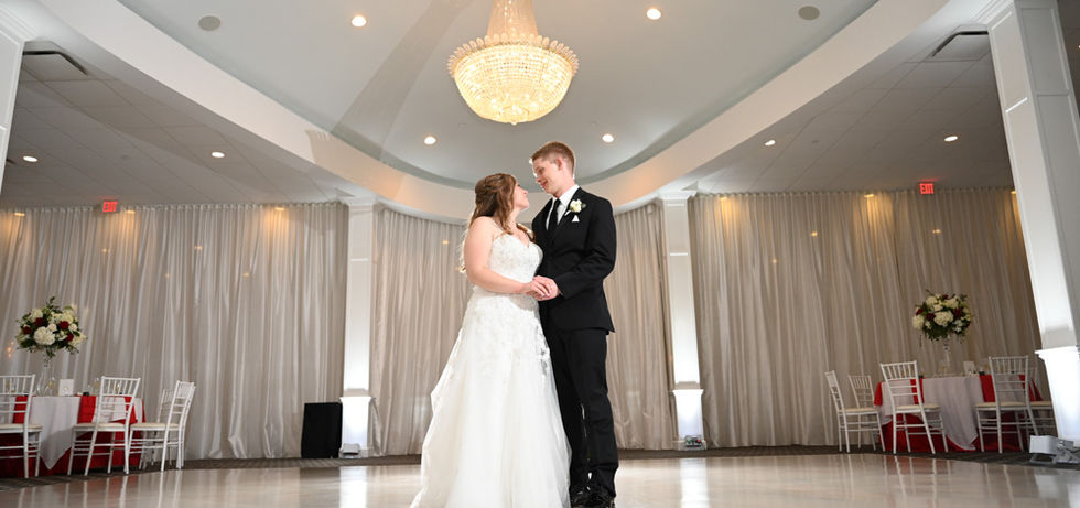 Bride and groom stand in the center of the pearl white dance floor with columns and domed ceiling holding up the grand chandelier over their heads at Avenir in Walpole MA by Saphire Event Group.