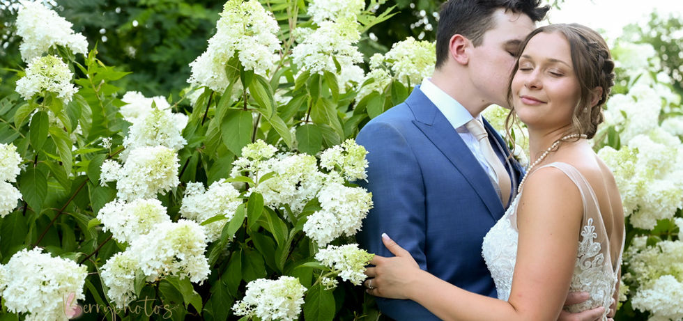Bride and groom nestled into a bush of flowers at Plimoth Patuxet formerly known as Plymouth Plantation
