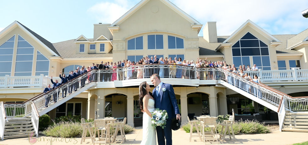 Iconic back grand staircase at Indian Pond in Kingston MA with guests lining the stairs and couple kissing in the foreground.