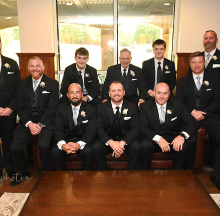 The groom surrounded by his groomsmen while sitting in the lower level of Indian Pond in Kingston MA on their plush couches with cherry wood lined walls.