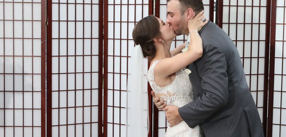 Bride and groom kissing inside their wedding ceremony at Jones River Trading Post in Kingston MA