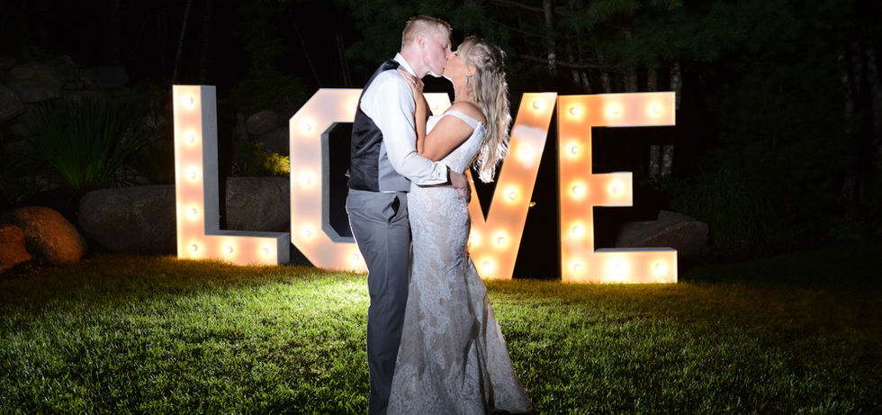 The love sign at night is all lit up. Where the bride and groom are standing is pitch black, so I put a flash behind them to set the area with some backlight and then another off-camera flash just to my side facing their fronts so they look perfect and the LOVE sign is still perfect as well.