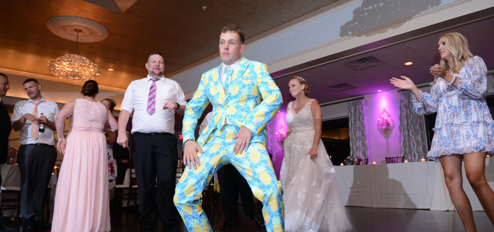 Groom is in a fun suit doing crazy dance moves on the dance floor of the Grand Ballroom at The Villa in East Bridgewater MA