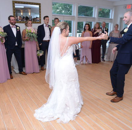 Bride and groom spin on the dance floor lined by the entire wedding party at Camp Bournedale in Bourne MA