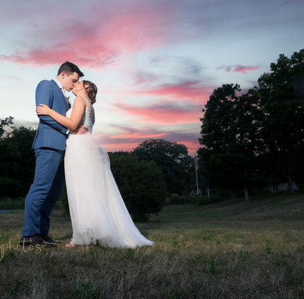The sky is blazing in colors as this bride and groom kiss at sunset at Plimoth Patuxet formerly known as Plymouth Plantation