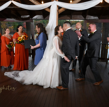 This couple is kissing at the end of their outdoor wedding ceremony at Camp Kiwanee in Hanson MA