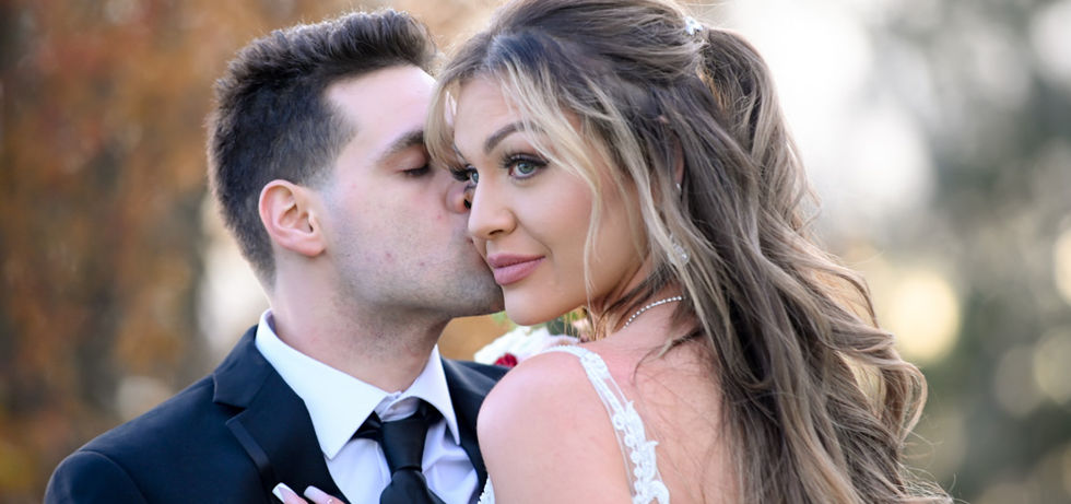 Natural light and airy shot of groom kissing the cheek of the bride as she looks to the left outside at the Madera Room of The Villa in East Bridgewater MA