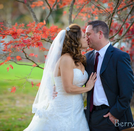 Bride and groom stand in front of a tree in full fall foliage at Camp Bournedale in Bourne MA