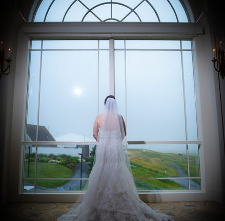 Bride stands in front of large decorative window at Granite Links in Quincy MA with outside exposed properly and flash hitting just the bride and her dress.