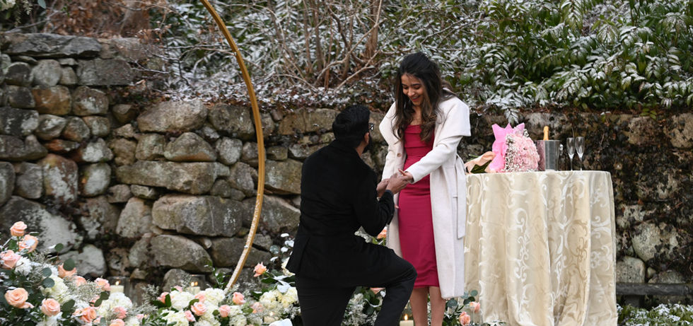 This groom drops to one knee to propose to his future bride in the horn blower gardens at Plimoth Patuxet formerly known as Plymouth Plantation in the winter.