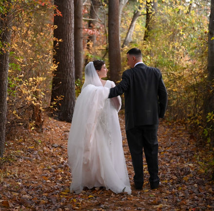 Bride and groom walking down the secret path that leads to the lake at Camp Kiwanee in Hanson MA with fall foliage all around.