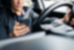 Conductor irresponsable texteando con el celular en la carretera, mostrando el peligro de accidentes y explicando por qué los seguros de auto están subiendo por distracciones al volante.